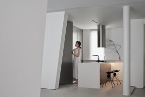 Modern, minimalist kitchen with white concrete surfaces, stainless steel appliances, and a sleek design.