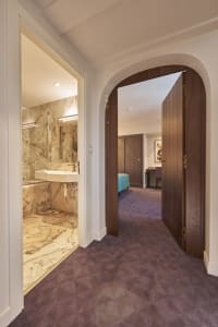 View of a luxurious marble bedroom suite, featuring elegant wooden doors and a contemporary design.