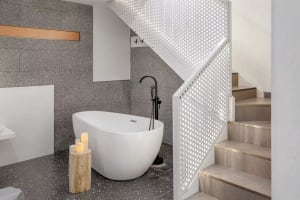 Modern industrial bathroom with a glass floor, freestanding bathtub, and minimalist styling.