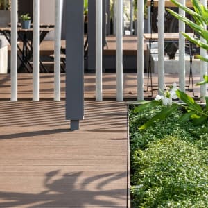 A wooden deck with metal railing, potted plants, and two chairs in a serene outdoor setting