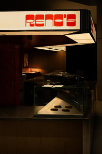 Industrial kitchen with a glass display case, bowls, and cups on a counter in a professional food preparation environment