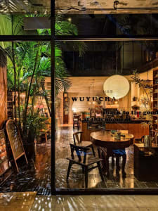 Warm and inviting cafe interior with a wooden table, potted plants, and natural light from a large window