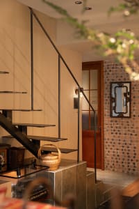 A classic staircase in a brick building with a wooden staircase and doorway leading to another part of the building