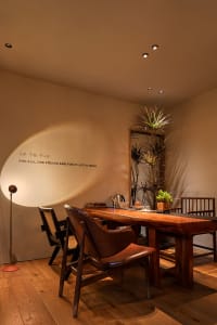 A warm and inviting dining area with a wooden table, three chairs, and two potted plants, perfect for meals and gatherings