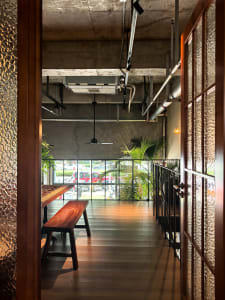 Warm and inviting restaurant interior with a wooden dining table, potted plants, and decorative vases, set against a busy background