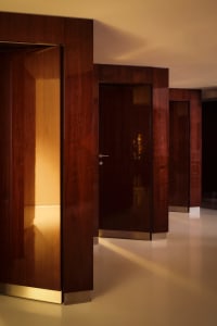 A well-lit hallway with three oak wood doors featuring glass windows, creating an inviting atmosphere