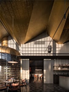 Modern bar area with gold ceiling and walls, wine glasses on countertops, and comfortable seating options