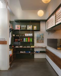Cozy restaurant interior with a green wall, tile floor, and various items displayed on shelves and a counter