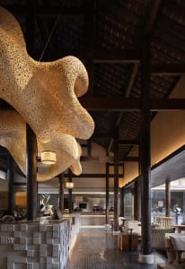 A warm and inviting interior space with wooden pillars, beams, and chairs around dining tables