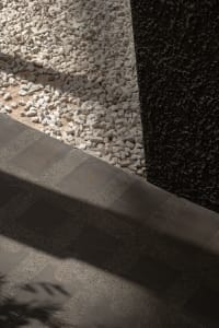 A hallway with a stone floor and scattered rocks, creating a natural and rustic ambiance with depth and contrast from the lighting