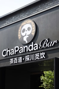 Modern Asian restaurant with a concrete exterior and a black sign with white lettering
