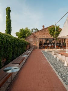 A brick walkway surrounded by dining tables, chairs, and benches in an inviting outdoor patio area