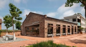 A historic brick building with a red roof and a large archway leading to a courtyard with benches for a serene and peaceful atmosphere