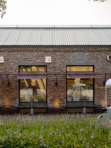 Old brick building with two large windows on each side of its facade, giving it a rustic appearance
