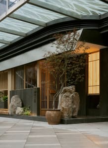 A serene Asian-style courtyard with a rock garden, potted plants, and a peaceful atmosphere