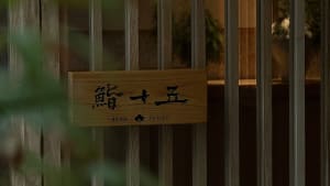 An Asian restaurant with wooden walls, a sign reading Sushi, and potted plants adding to the inviting and comfortable atmosphere