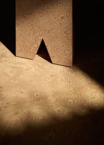A modern living space with a unique wooden floor featuring an 'A' shape design, set against a neutral background