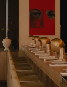 Elegant dining space with a long wooden table, multiple chairs, wine glasses, and cups, set in a sophisticated atmosphere