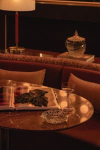Cozy living area with a couch, dining table, books, wine glasses, and vases, featuring warm and inviting atmosphere