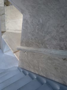 A real photo of a staircase in a building with concrete steps, a white stairwell, and natural light from an unknown direction