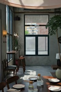 A cozy cafe with a large window, chairs, a dining table, and potted plants, perfect for enjoying a meal or coffee