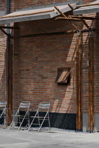 A brick building with a patio seating area featuring four chairs arranged in two rows, creating a casual and inviting atmosphere