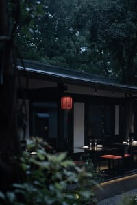 Modern restaurant interior with black walls, a red accent wall, and dining tables with wine glasses