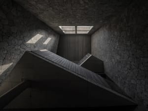 A dark and moody staircase with concrete stairs and no natural light