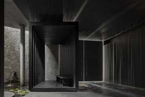 A dark public space with a wooden doorway and a metal-framed bench, possibly a waiting area within a building