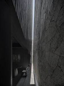 A narrow hallway with three black chairs placed along the walls, suggesting a residential or office space