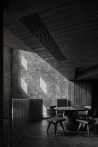 A dark and moody dining area with multiple tables and chairs, creating a cozy atmosphere for patrons