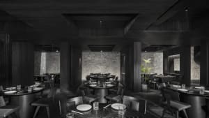 Modern restaurant interior with dark wood elements, black accents, and potted plants, creating an elegant and inviting atmosphere