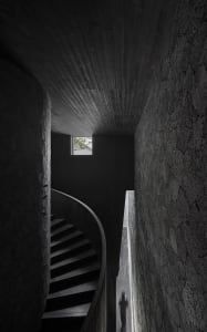 A darkened room with a spiral stone staircase, creating a mysterious atmosphere