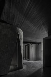 A dimly lit hallway with stone walls, featuring two darkened rooms with doors on either side