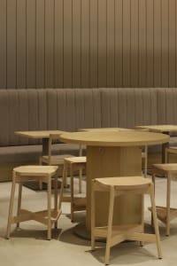 Warm and inviting restaurant interior with wooden tables and chairs, multiple benches, and a central dining table
