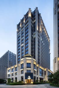A large building with a mix of modern and contemporary design elements, featuring a predominantly stone exterior and numerous windows in a city environment