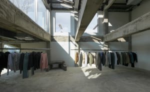 Open clothing store with multiple racks and benches, displaying a variety of garments and accessories