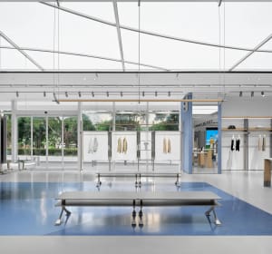 Open modern retail space with white interior, clothing items on display, and benches for seating