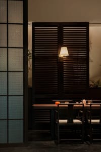 A cozy dining area with a wooden table surrounded by chairs, featuring various items and vases, in a dimly lit environment