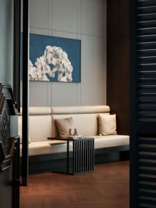 Cozy living space with a white couch, a black chair, vases, and books, featuring a painting on the wall