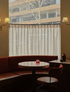A cozy restaurant interior with a dining table surrounded by chairs, a glass of red wine, and inviting atmosphere