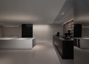 Commercial kitchen with white walls and floors, featuring modern appliances and minimalistic design