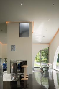 Open living area with white walls, chairs, a couch, dining table, refrigerator, and sink, well-lit and inviting