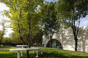 An inviting outdoor patio with two round wooden tables and four chairs, arranged for socializing and dining