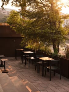 A restaurant patio with black tables and chairs, surrounded by an inviting atmosphere