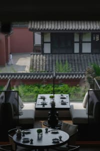 Cozy Asian restaurant with a large dining table, red wall, and tiled roof, set up for a meal