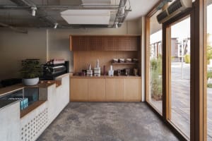 A modern retail space with wooden shelves and cabinets displaying various items, natural light from large windows, and a clean and organized atmosphere