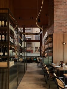 Elegant restaurant interior with a dining area, bar, and wine bottles, featuring a sophisticated atmosphere and comfortable seating