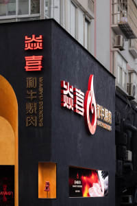 A modern Asian restaurant with a black exterior, red accents, and a large window for natural light, located in an urban area with a nearby streetlight