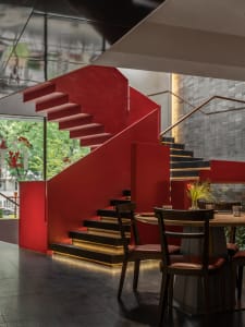 Warm and inviting interior staircase with wooden steps, black railing, and two chairs, set against a backdrop of red walls